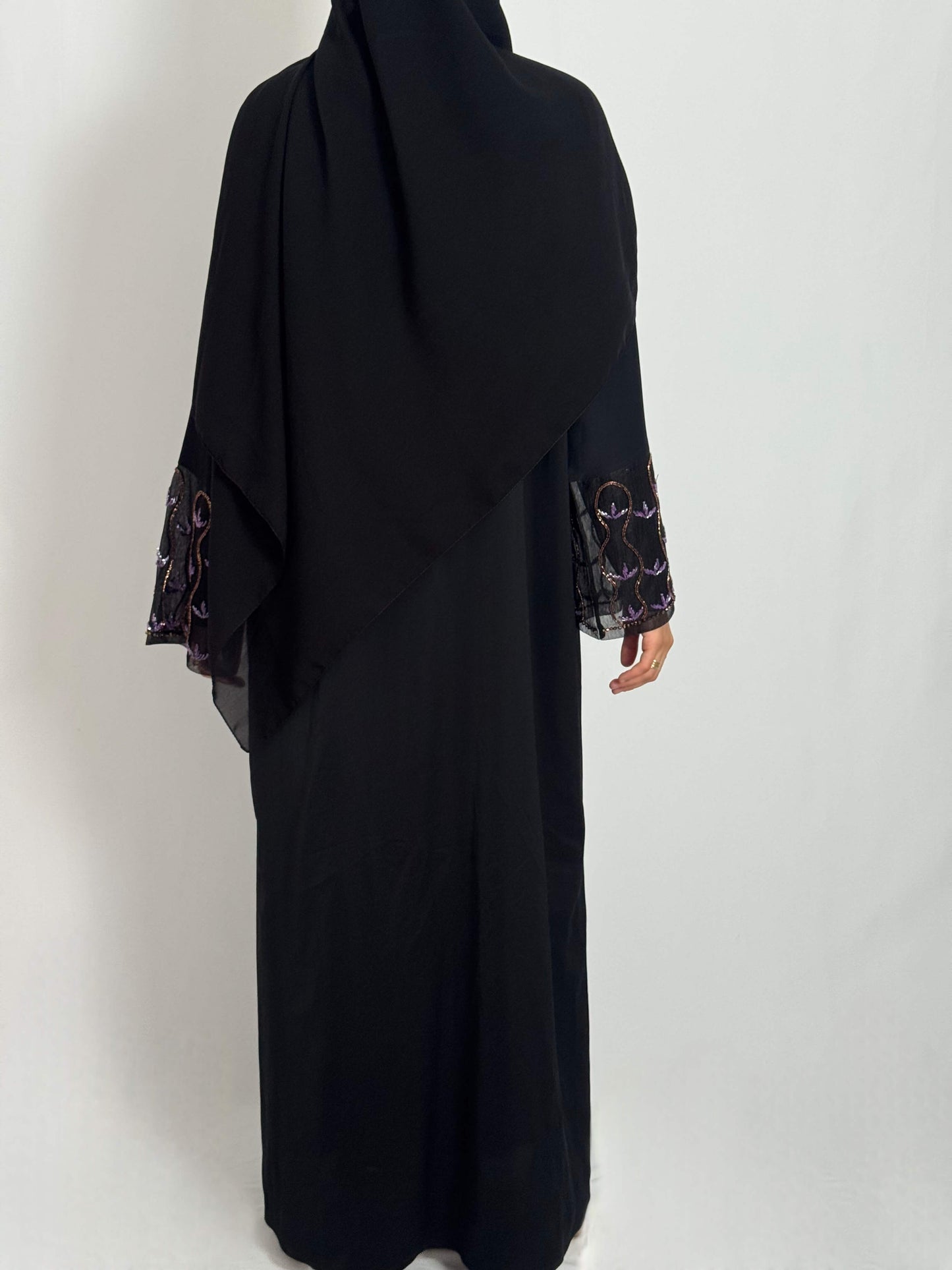 Abaya leila fluide et élégante tissus nidha vue de dos portée par une femme voilée sur fond blanc. abaya brodée aux manches.