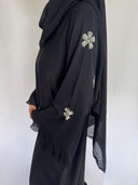 Zoom sur les manche de la abaya nejma noir et ses broderie argenté en fleur. protée par une femme voilée elegante