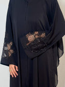 Zoom sur abaya noire avec dentelle fleuri en transparence sur les manches et perlage fait à la main